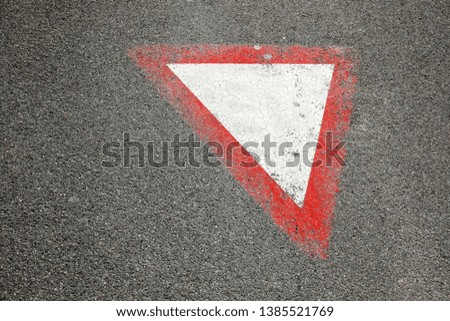 This road sign, which has been painted on the asphalt surface of the street and it says: Give Way.