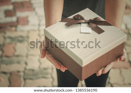 Women holding a gift box Brown ribbon in the top view lawn