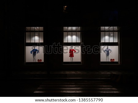 The enlightened windows of a clothes store with silhouettes. 