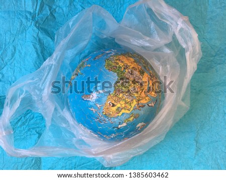 Globe in plastic plastic wrap on a blue background.  concept of environmental pollution by plastic waste, environmental problems.  stop the plastic pollution of the planet.
