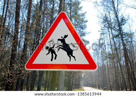 Warning road sign of a possible attack by wild elks on humans. Sign about of wild moose on a forest road. Royalty-Free Stock Photo #1385613944