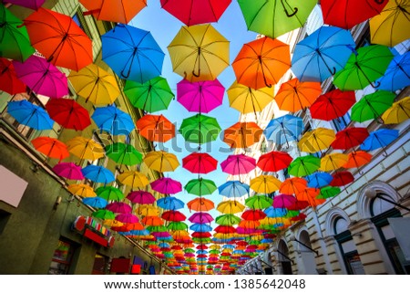 Colorful umbrellas hanging out above the old streets of Timisoara city center, Romania. Photo taken on 21st of April 2019. Royalty-Free Stock Photo #1385642048