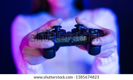 Gamer Concept. Girl holding gamepad, neon blue and pink light, closeup