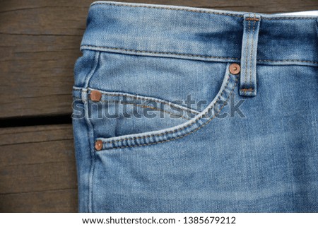 Close up of denim blue jeans pocket on wooden background


