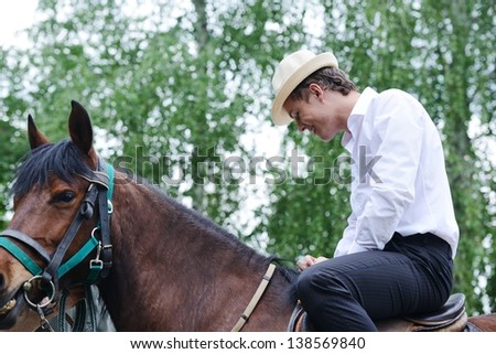 Young stylish man taking riding a horse on countryside