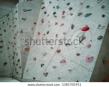 Grey wall with colourful climbing holds for rock climbing activity.