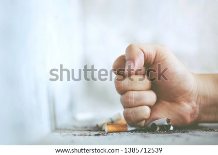 Man hand fist destroy break  refusing cigarettes. concept for quitting smoking and healthy lifestyle.or No smoking campaign. cigarette butt on Concrete floor, bare cement. Royalty-Free Stock Photo #1385712539