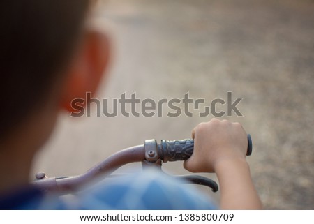 hand of cute boy and bicycle with nature background. subject is blurred.