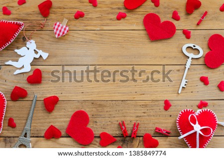 Red felt hearts and cupid angel border arrangement with copy space. Flat lay Happy Valentines day concept on wooden background