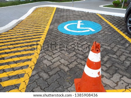 Blue sidewalk painting with yellow stripes and a cone, informing the driver that parking is for wheelchair users. Education and respect for the disabled.