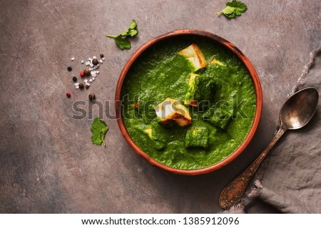 Palak paneer or Spinach and Cottage cheese curry on a dark background. Traditional Indian food. Top view, copy space Royalty-Free Stock Photo #1385912096