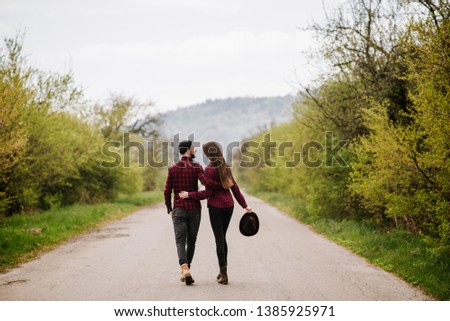 A couple walking by the road at the country side. Back view