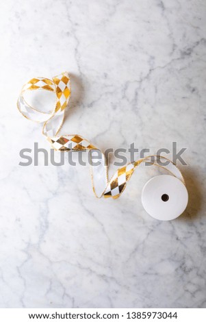 Coil of white and gold ribbons on a marble background