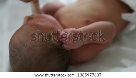 Newborn baby suckling on finger, calming effect on infant.