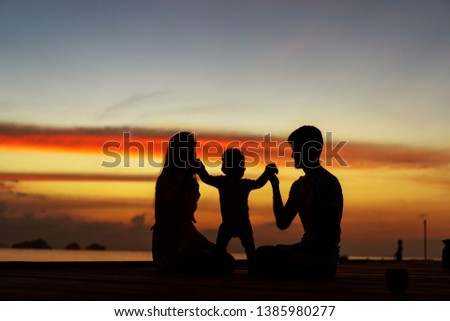 Family in love with son hugging at sunset, silhouette