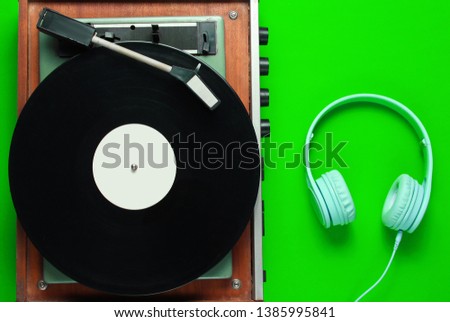 Retro vinyl record player, headphones on green background. Top view. Retro style. Flat lay