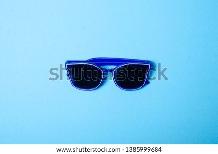 Blue sunglasses fashion on color blue background, top view