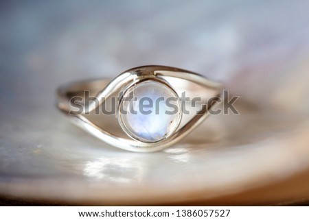 Elegant female silver ring on natural shell nacrous background