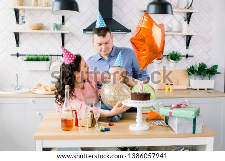 Young happy Caucasian family celebrating a first birthday party of their little baby boy
