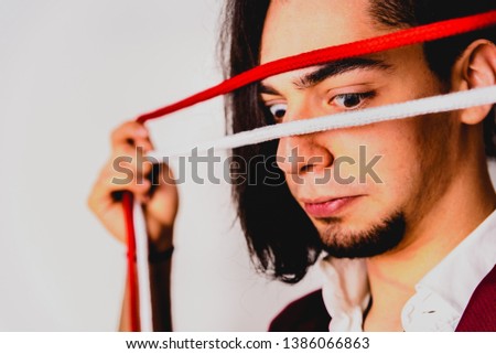 Portrait of young magician handling ropes and bandanas to do magic tricks, isolated on white.