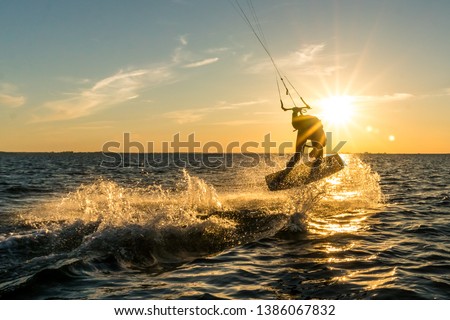 kitesurfer doing tricks in sunset Royalty-Free Stock Photo #1386067832