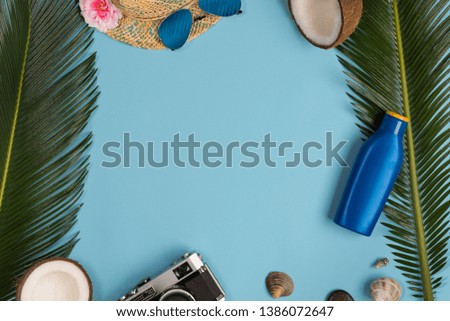 sunscreen, glasses, hat on blue background, top view.