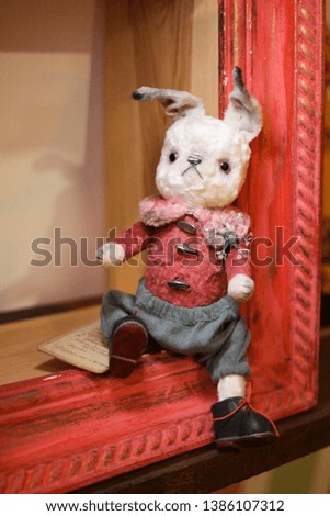 Handmade toy rabbit sitting on the  shelf. Toys for children. Vintage toys