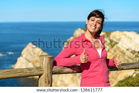 Happy woman sitting and relaxing on sea and coast landscape background. Pensive girl enjoying peace and silence on nature summer vacation. Asturias, Spain.