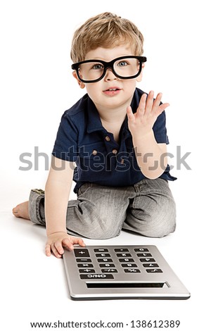 Cute boy wearing bit glasses doing maths with fingers and calculator.