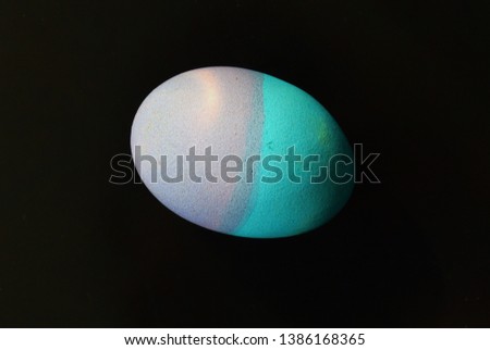 Photo background for Easter. Egg, painted in two colors on a dark background