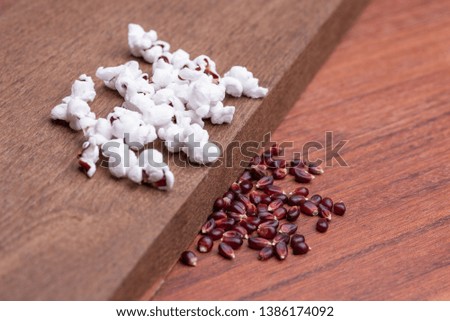 Raw Organic Ruby Red Popcorn. Latin name "Zea mays everta" isolated on wooden background, angle view, copy space.