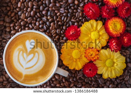 Coffee cup with Coffee beans background with colorful flower. Freshly brewed coffee in a restuarant