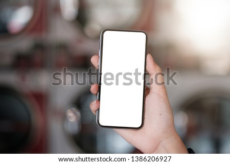 Woman hands using smartphone mockup at the laundromat shop
Laundry Shops. Blank screen mobile phone for graphic display montage