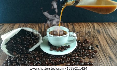 White hot coffee, laid around with freshly roasted black coffee beans, fragrant, ready to serve customers in the morning in the cafe is popular on wooden floors.