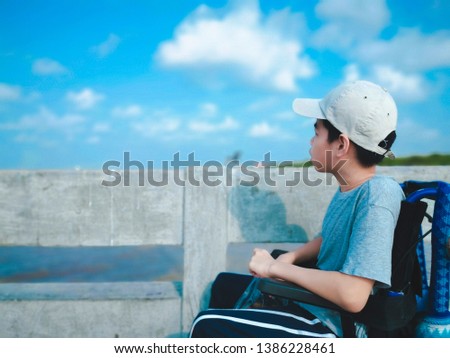 Child on wheelchair waiting to see seagull, He held the bird's food in his hand and excited on the bridge background, Life in the education age of disabled children, Happy disabled kid concept.