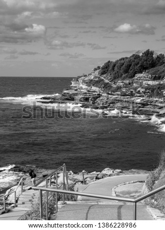 monochrome picture of A fisherman fishing on a rocky beach with multiple fishing line on a nice morning