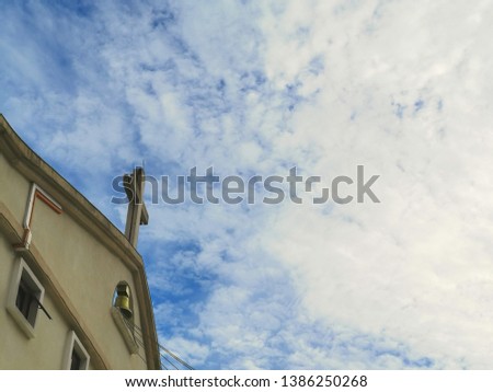 Church rooftop cross with blue cloudy sky as background. 