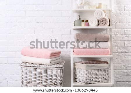 Shelving unit and baskets with clean towels and toiletries near brick wall Royalty-Free Stock Photo #1386298445
