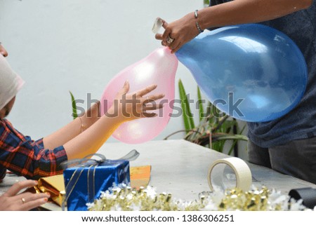 close up portrait of women hand holding red balloon and wrapping gift preparing birthday surprise party while sitting on the concrete table -image