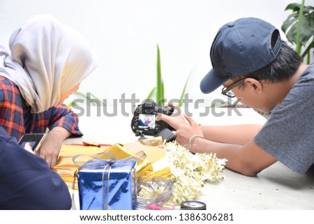 interaction between male photographer with two hijab female explaining birthday gift concept and image from dslr camera -image
