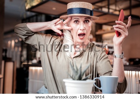 Wearing straw hat. Stylish well maintained old lady wearing green blouse and actively gesturing
