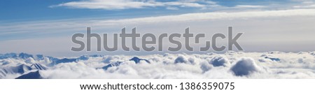 Panoramic airplane view of snowy mountains covered with beautiful sunlight clouds at sunny winter day. Caucasus Mountains, Georgia, region Gudauri. 