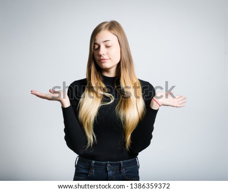 Confused woman. portrait of beautiful girl doubts in choice, studio photo on gray background