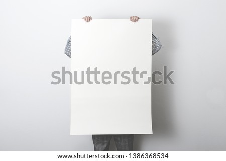 man holding white customizable empty poster Royalty-Free Stock Photo #1386368534