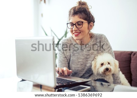 Young woman working at home. She is with her dogs Royalty-Free Stock Photo #1386369692