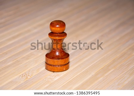 Chess, black pawn. Light wood background, close-up photo.