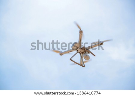 Close up of hovering drone against clear blue sky with clouds taking pictures.