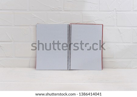 Empty notepad on white brick wall background