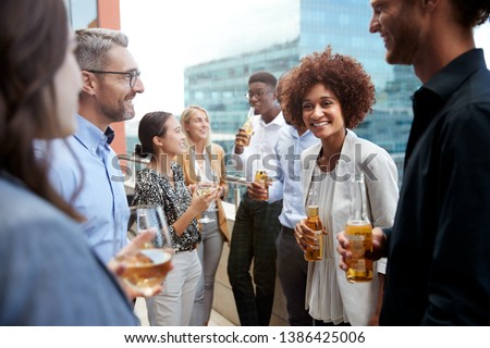 Business colleagues talking and drinking together on a balcony in the city after work Royalty-Free Stock Photo #1386425006