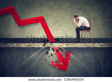 Depressed business man looking down at the falling red arrow going through a concrete floor. Fall and depreciation concept. Royalty-Free Stock Photo #1386446054
